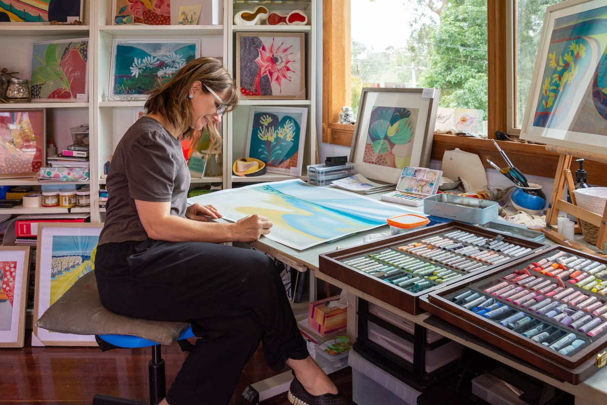Vivienne Fiori working at a table surrounded by drawings and studio materials.
